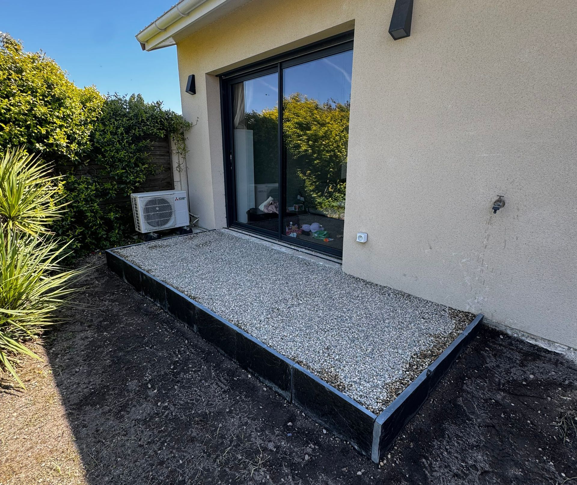 Petite terrasse devant la porte-fenêtre d'une maison.