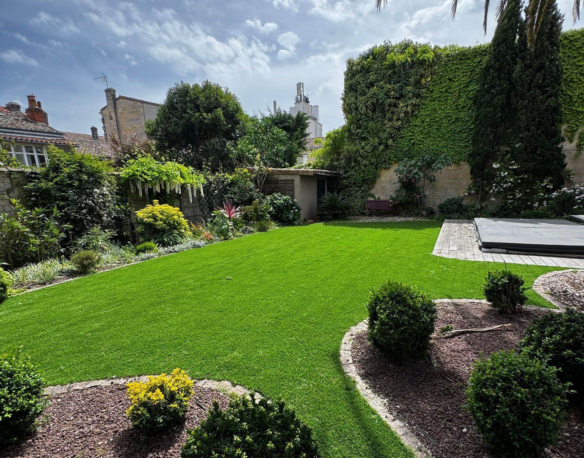 Jardin avec pelouse et petits arbustes à proximité d'une piscine recouverte.