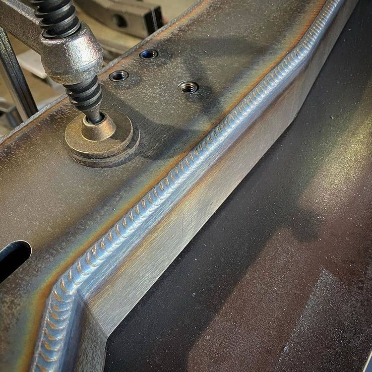 Primer plano de una estructura metálica soldada. La soldadura es una línea recta que une dos piezas metálicas.