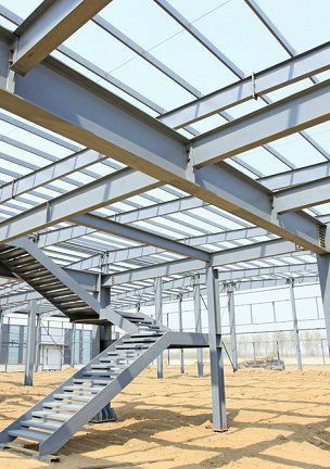 Estructura de acero de un edificio en construcción, incluidas vigas de soporte, una escalera y un techo transparente.