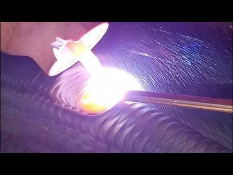 Soldador que utiliza un soplete para crear una soldadura, luz brillante y chispas visibles, toma de primer plano.