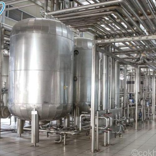 Tanques y tuberías industriales de acero inoxidable en un entorno de fábrica.