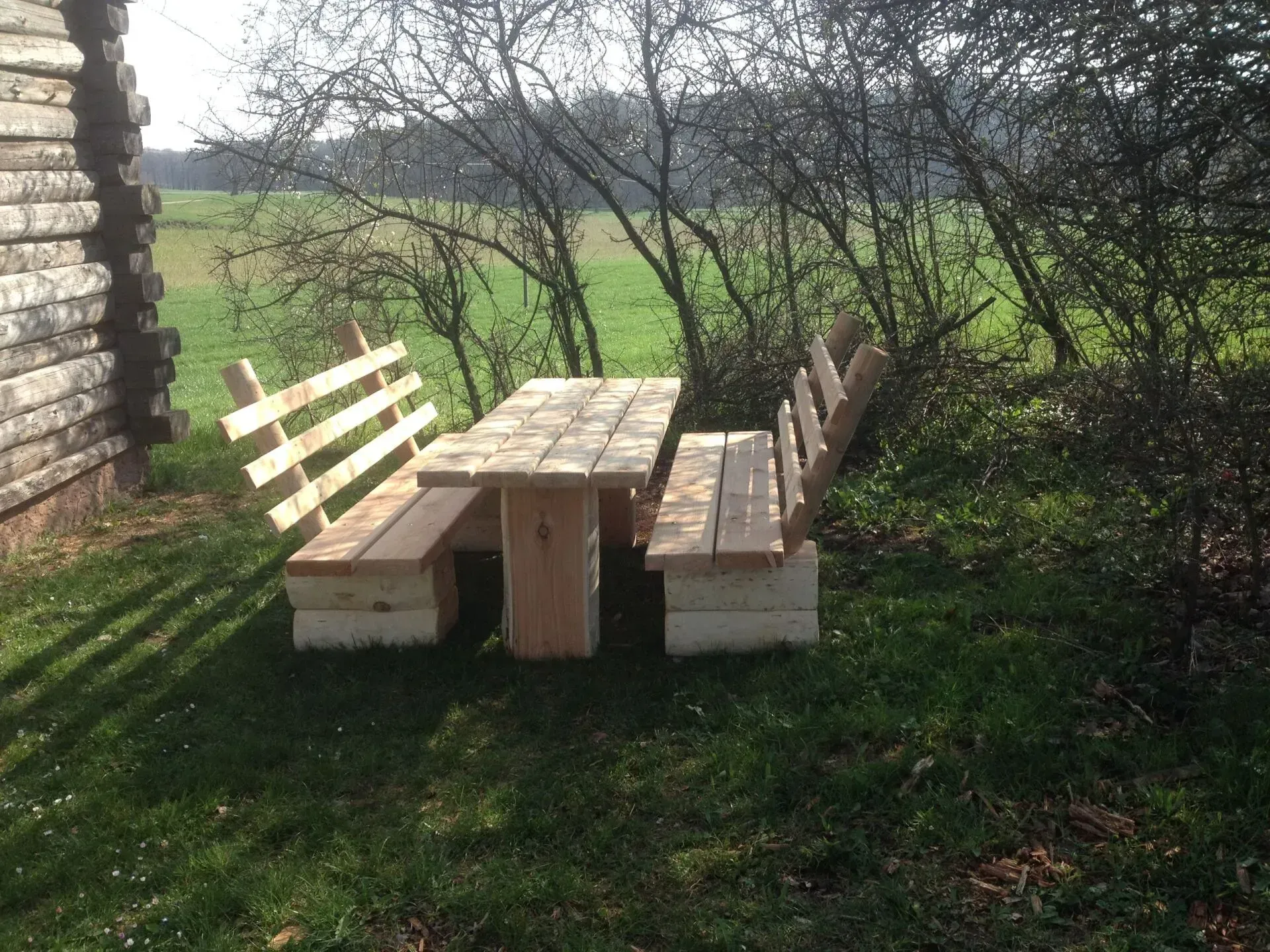Gemütliche Sitzbänke und Holztisch auf einer Rasenfläche vor einem Haus