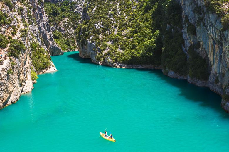Lagon entre des falaises rocheuses, avec un petit kayak au centre.