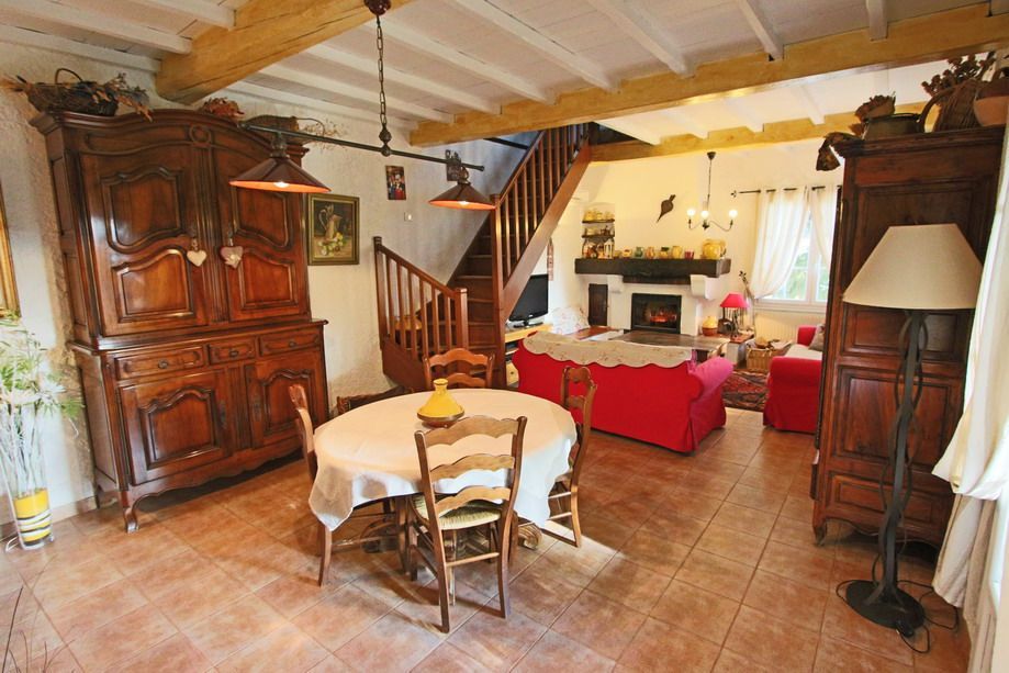 Salon rustique avec meubles en bois, sol carrelé, cheminée et canapé.