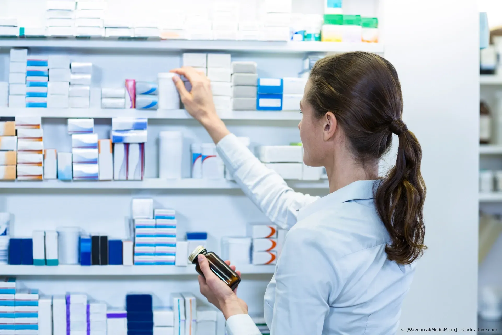 Ein Apotheker räumt Medikamentenpackungen in Regale in einer Apotheke ein.