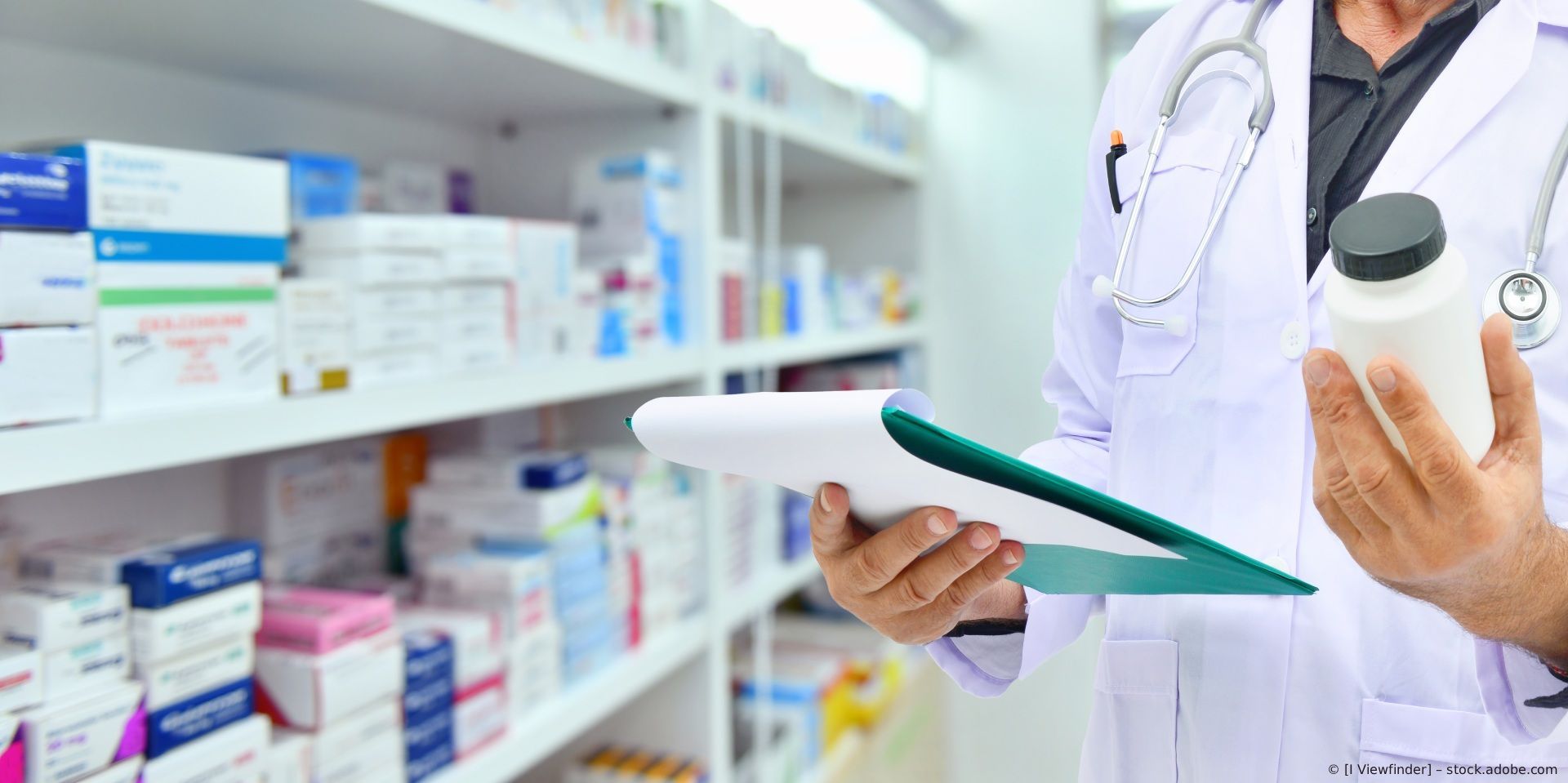 Apotheker mit Klemmbrett und Medikamentenflasche in einem Apothekengang