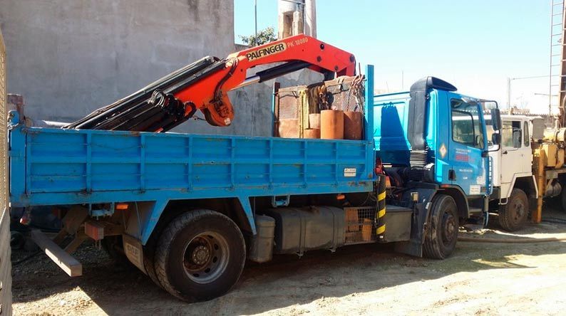 Un camión azul con una grúa en la parte trasera está estacionado en un estacionamiento.