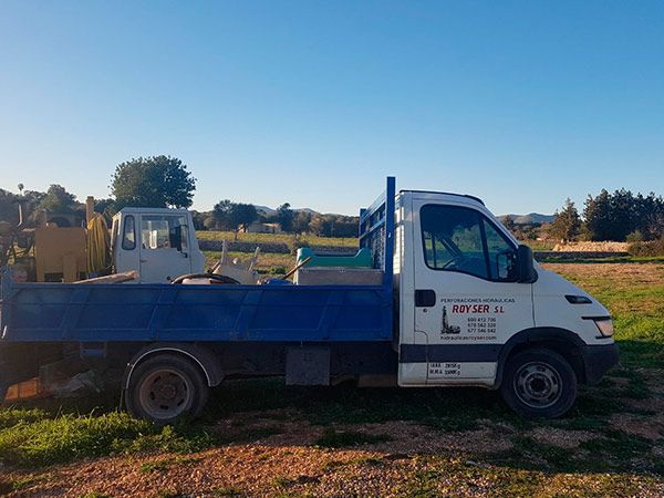 Un camión azul y blanco está estacionado en un campo de hierba.