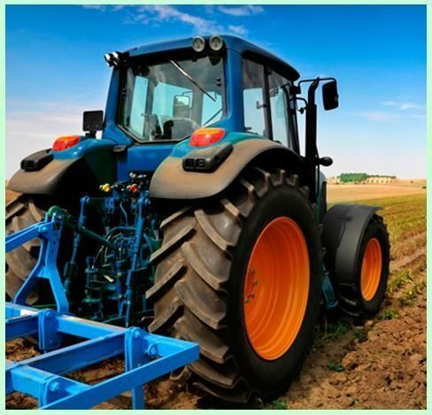 Un tractor azul y naranja está arando un campo