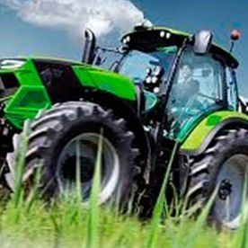 Un tractor verde conduce a través de un campo de hierba.