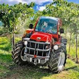 Un tractor rojo circula por un campo de hierba.