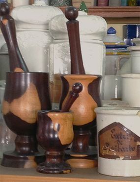 Morteros y pilones de madera con frascos en un estante. Tonos marrones y madera clara.