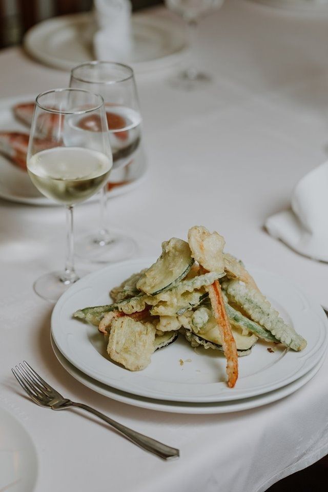 Un plato de comida y una copa de vino en una mesa.