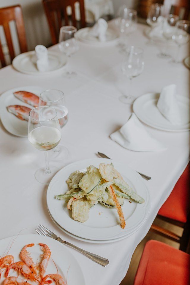 Una mesa larga con platos de comida y copas de vino sobre ella.