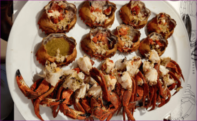Un plato blanco cubierto con cangrejos y pan sobre una mesa.