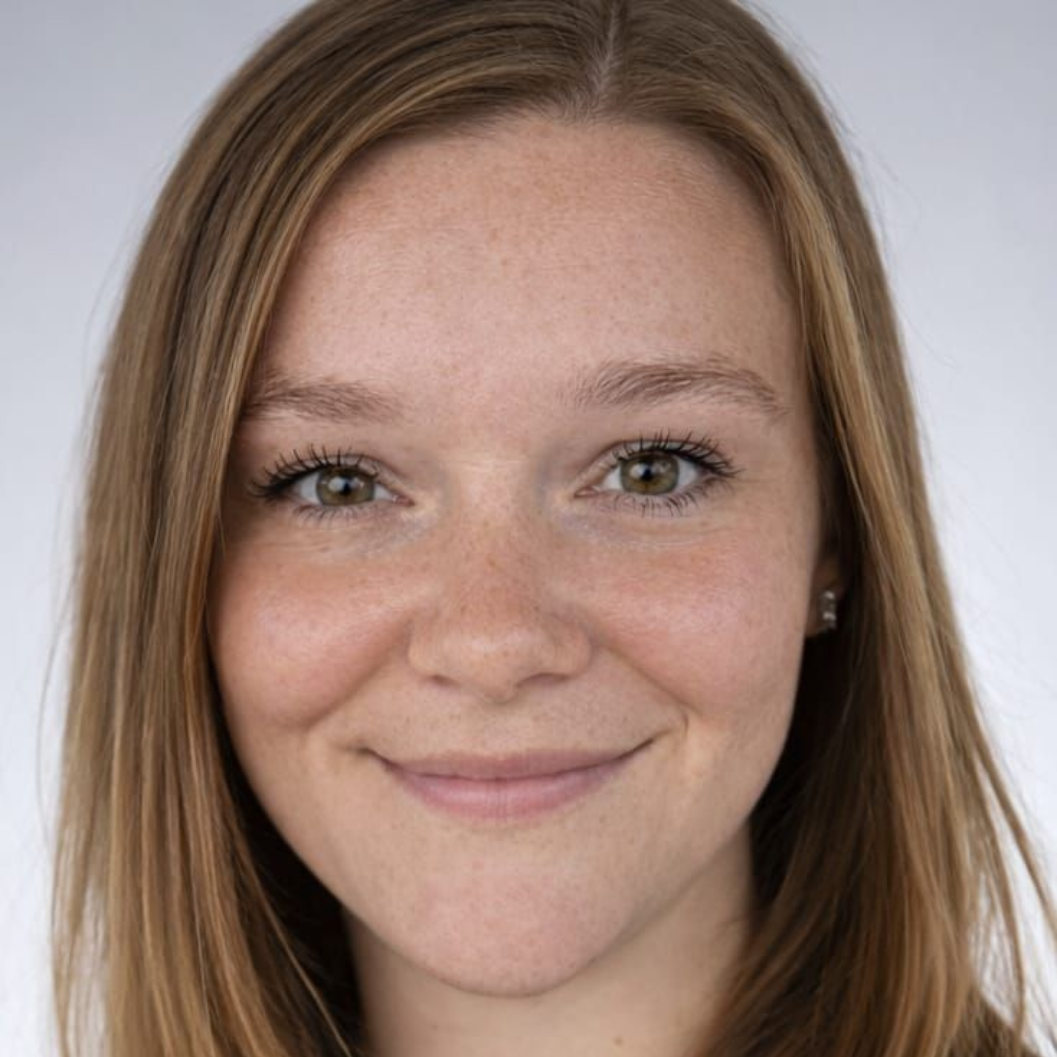 Junge Frau mit langen Haaren und Sommersprossen blickt in die Kamera