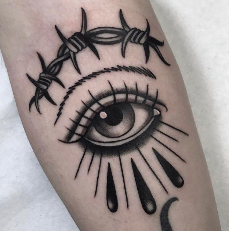 Un tatuaje de un ojo con alambre de púas alrededor.
