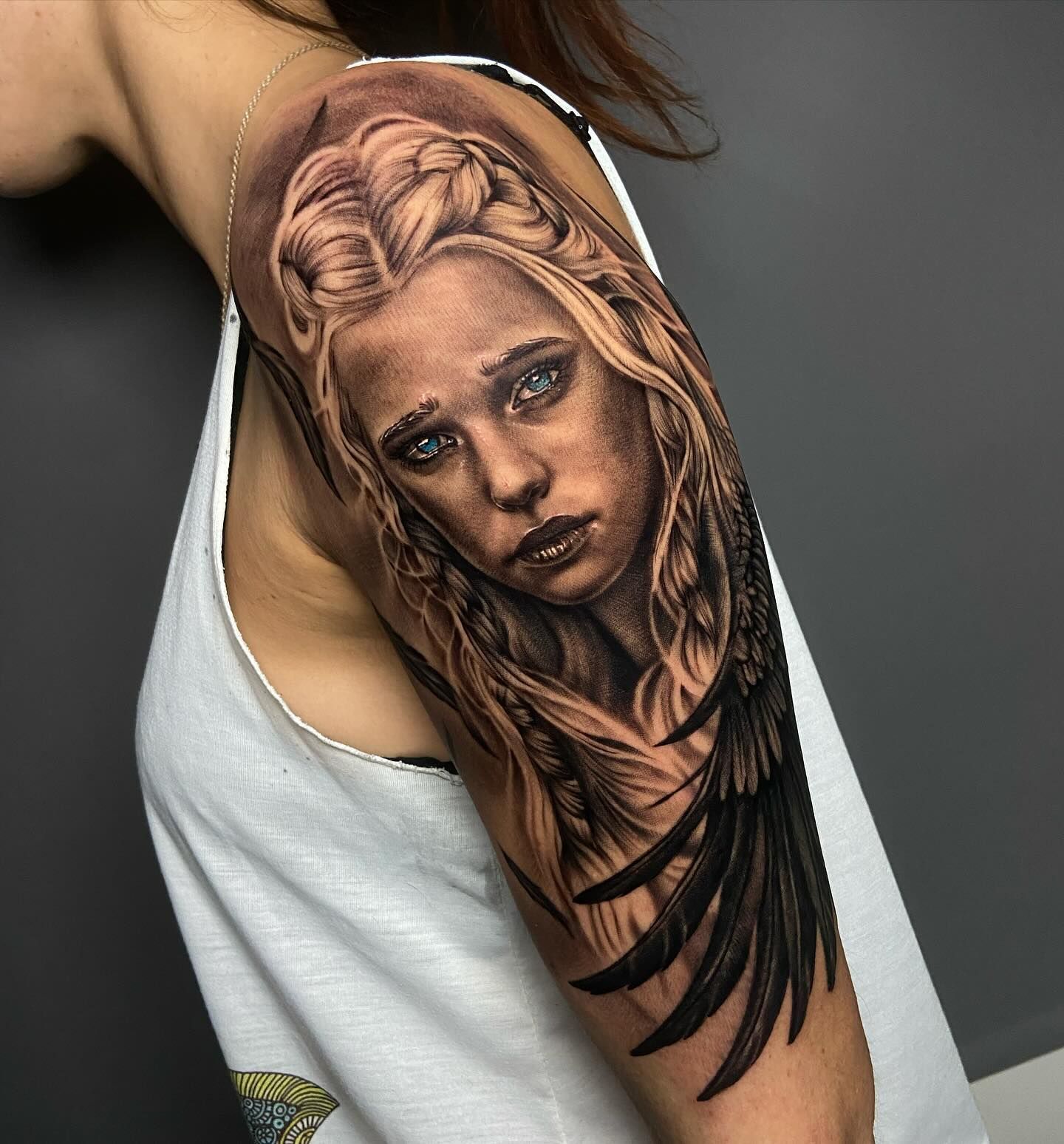 Una mujer tiene un tatuaje de una mujer con alas en su brazo.