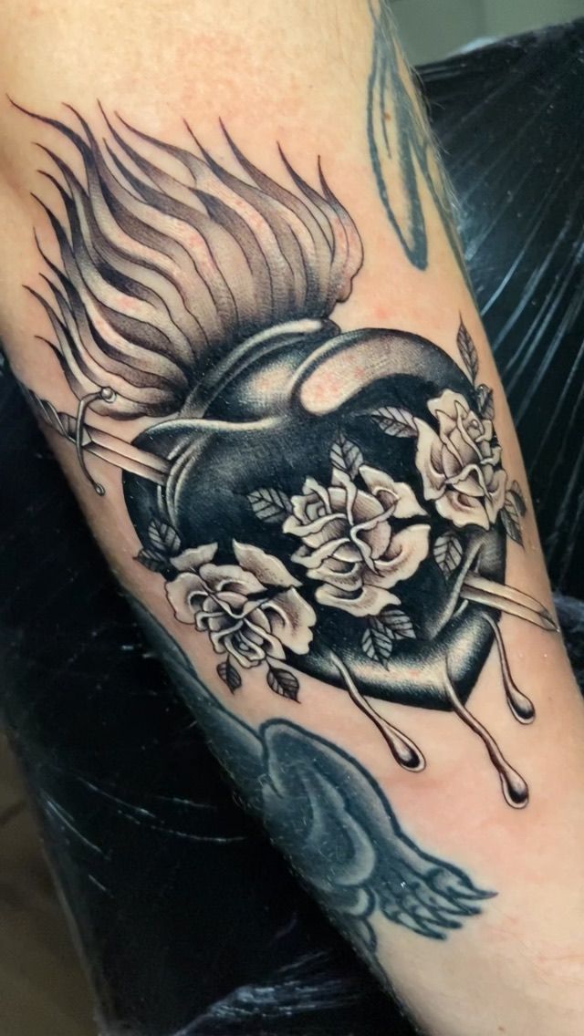 Un tatuaje en blanco y negro de un corazón con rosas.