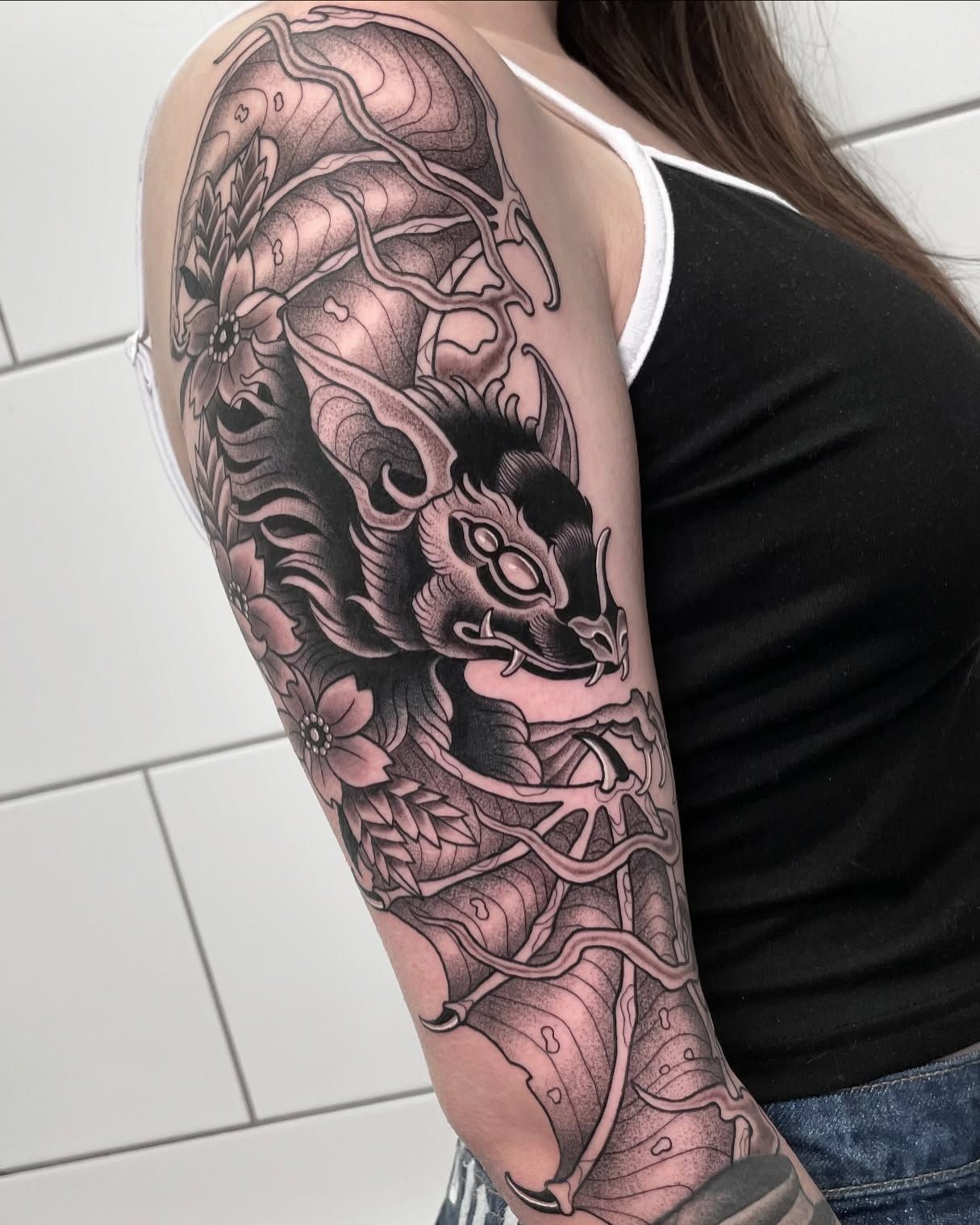 Una mujer tiene un tatuaje de un murciélago en el brazo.