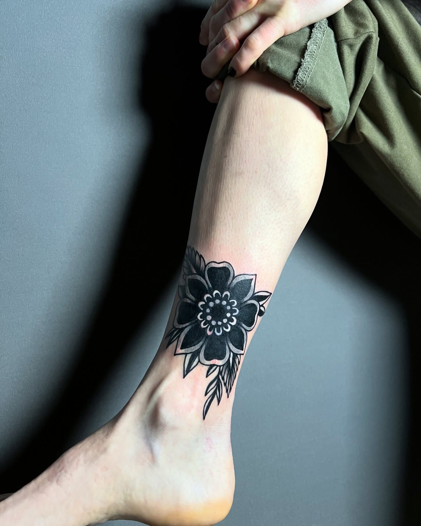 Una persona tiene un tatuaje de flor negra en la pierna.