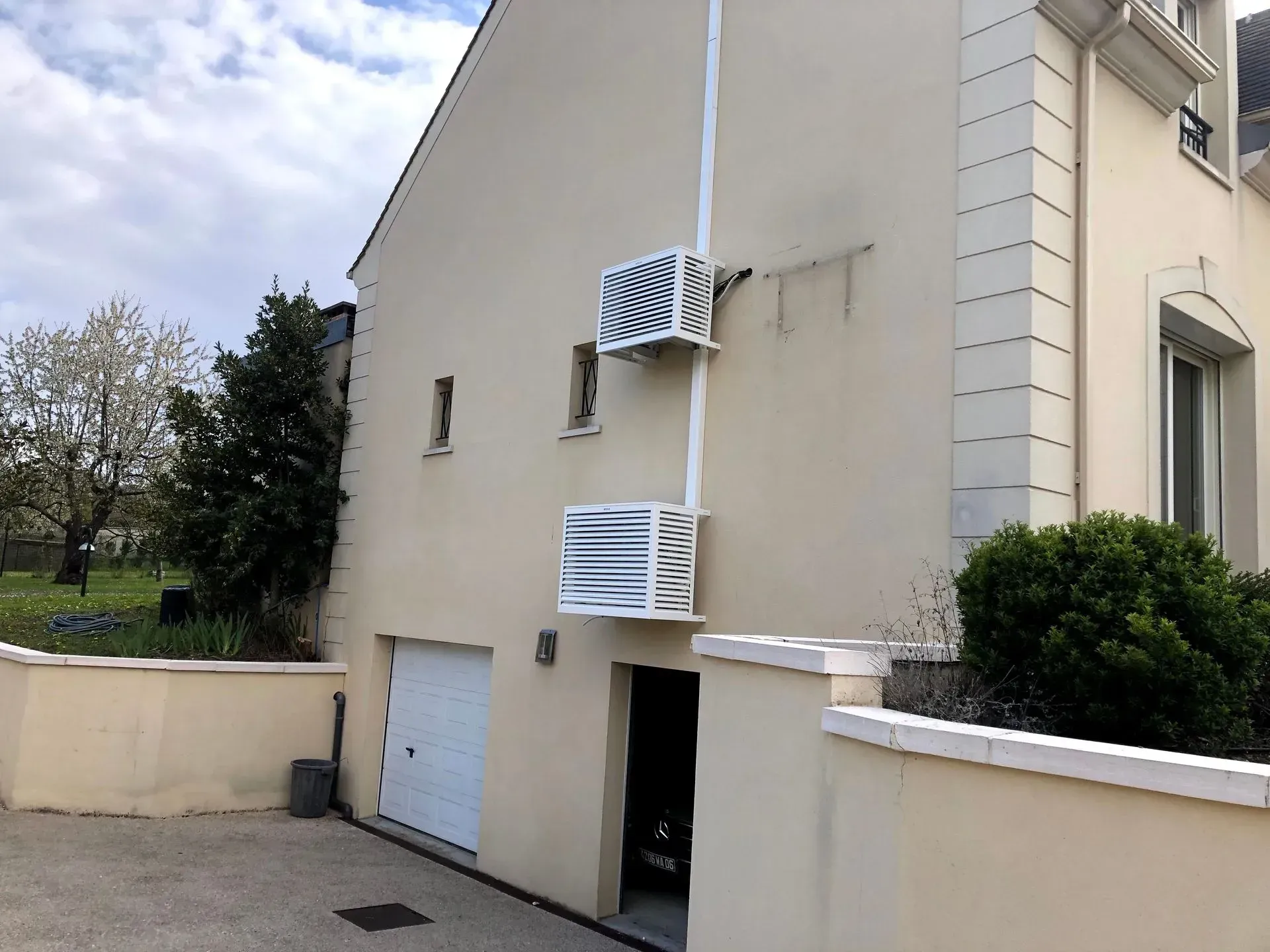 Maison à l'extérieur beige avec deux unités de climatisation blanches superposées verticalement.