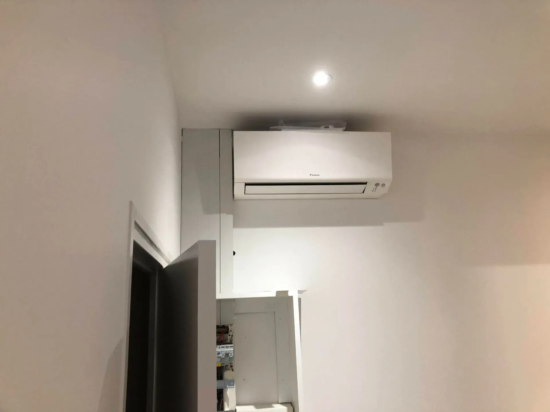 Climatiseur blanc fixé au mur au-dessus d'une porte. Intérieur aux murs blancs.