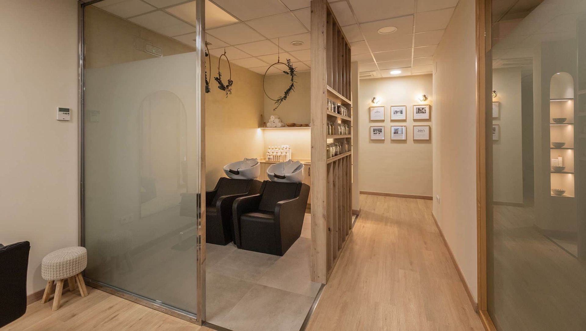 Interior de salón con puerta de vidrio esmerilado, sillas y un pasillo con decoraciones de pared.