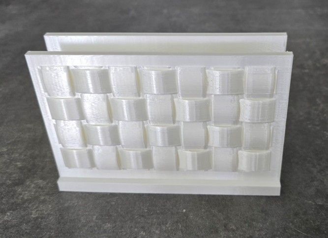 Pannello murale geometrico bianco stampato in 3D con motivo a blocchi ripetuti su una superficie scura