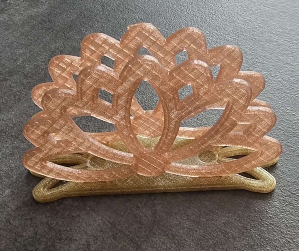 Cesto decorativo finemente intrecciato color pesca e oro su una superficie grigia