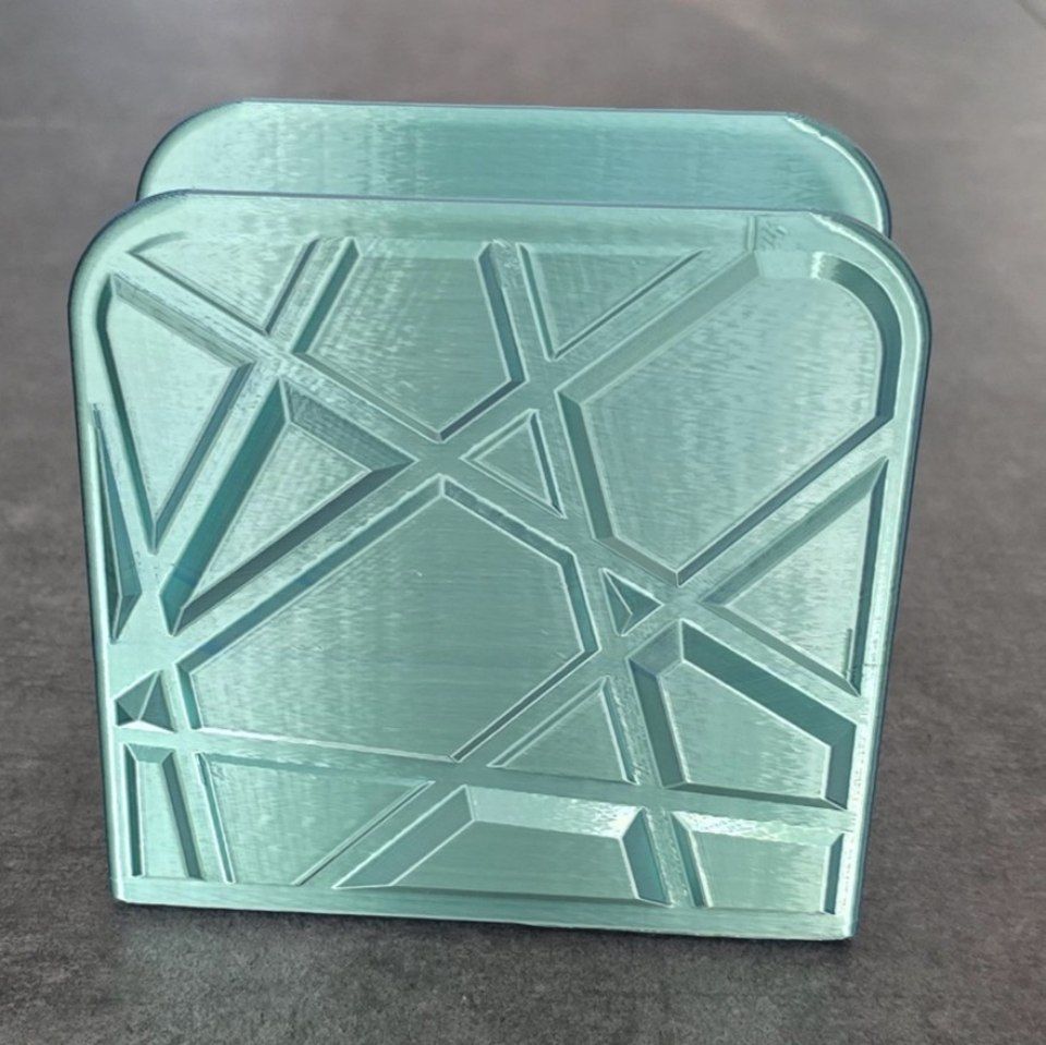 Scatola o contenitore quadrato con motivo geometrico azzurro su sfondo grigio.