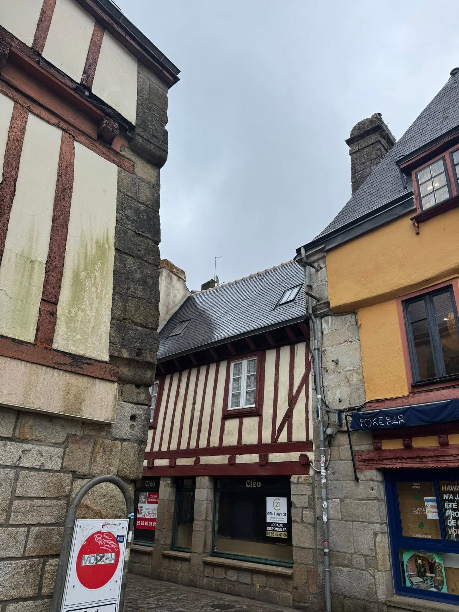 Rue médiévale étroite bordée de maisons à colombages et sol pavé.