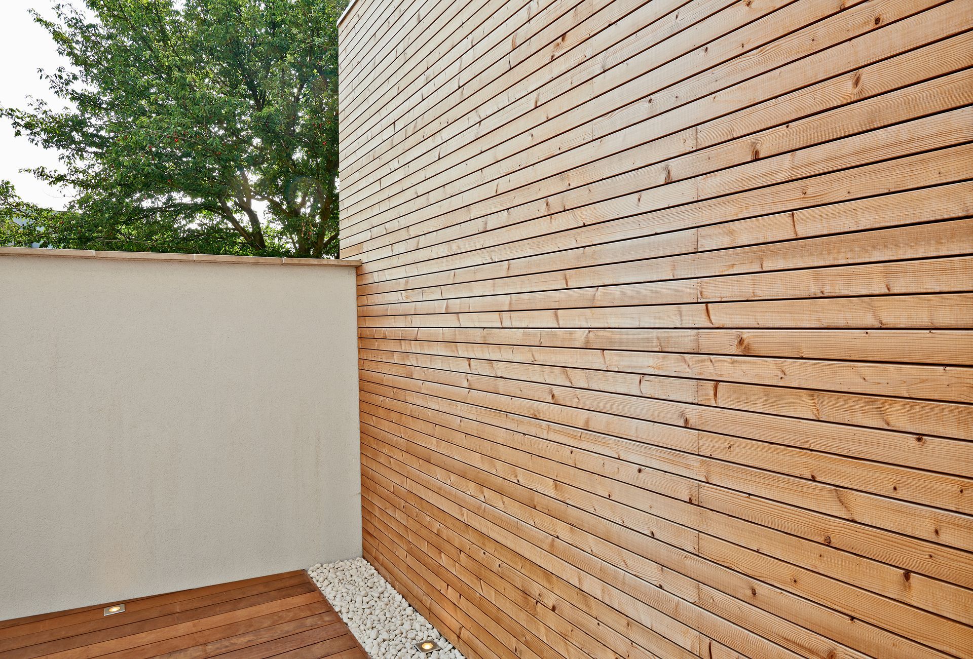 Terrasse moderne en bois avec mur en stuc blanc.