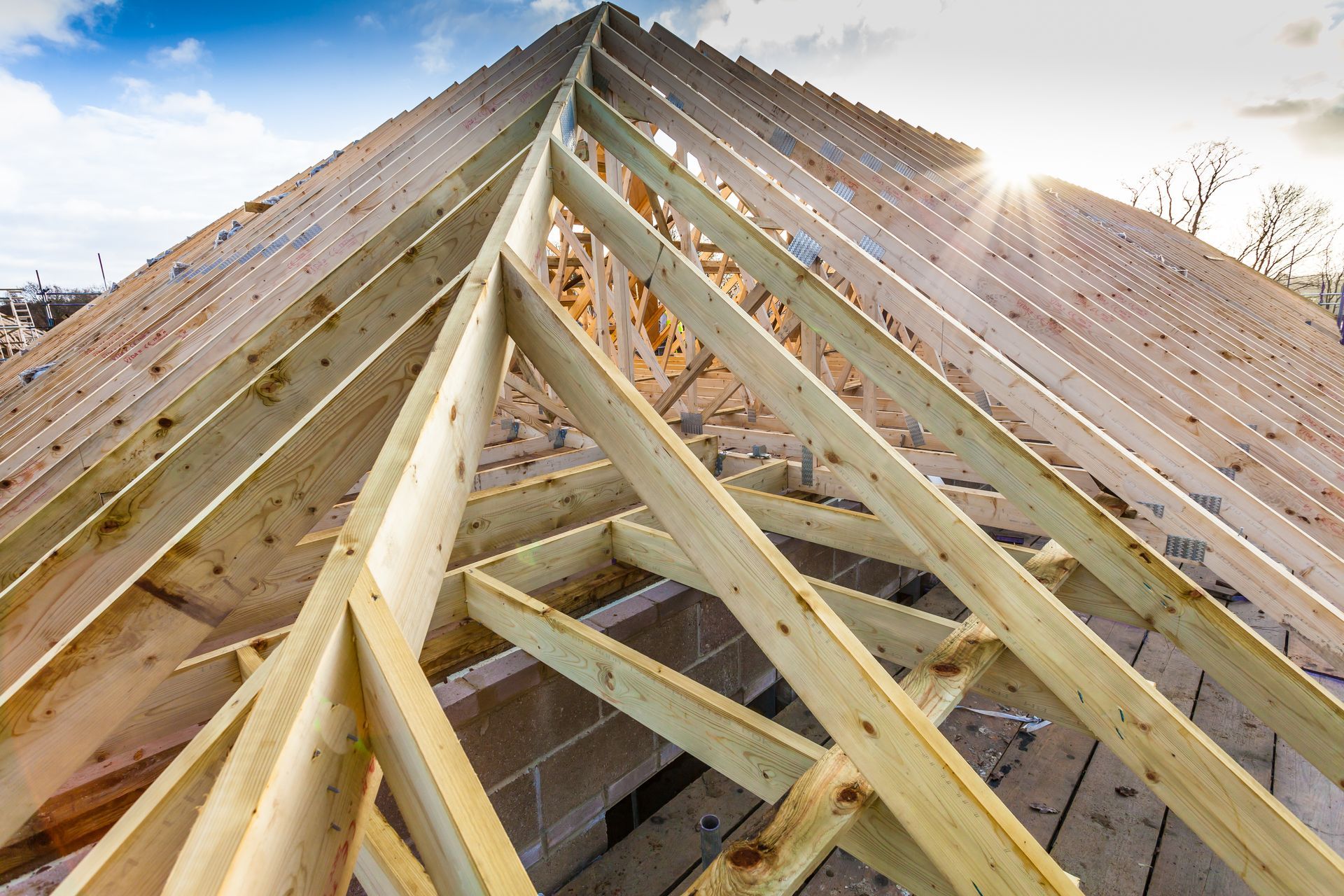 Charpente de toit en construction, avec fermes en bois apparentes.