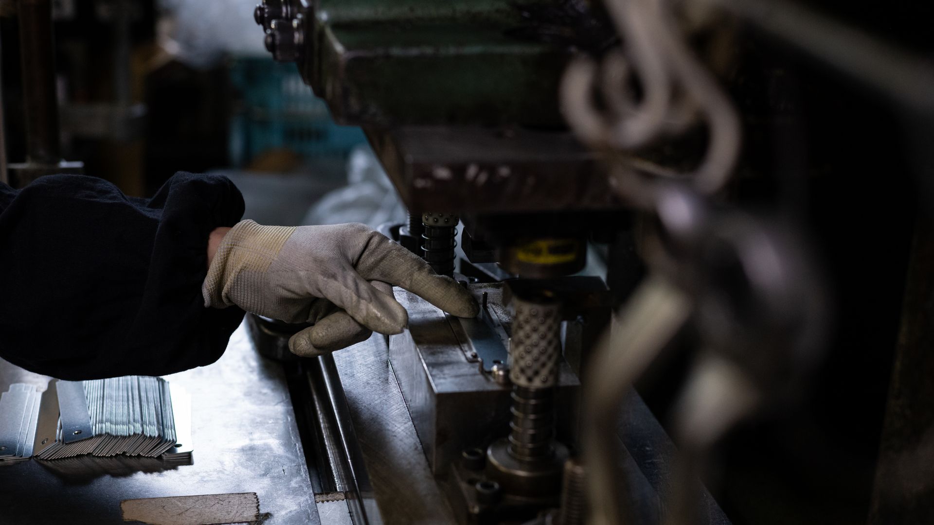 Main gantée utilisant un outil sur une machine dans un atelier faiblement éclairé