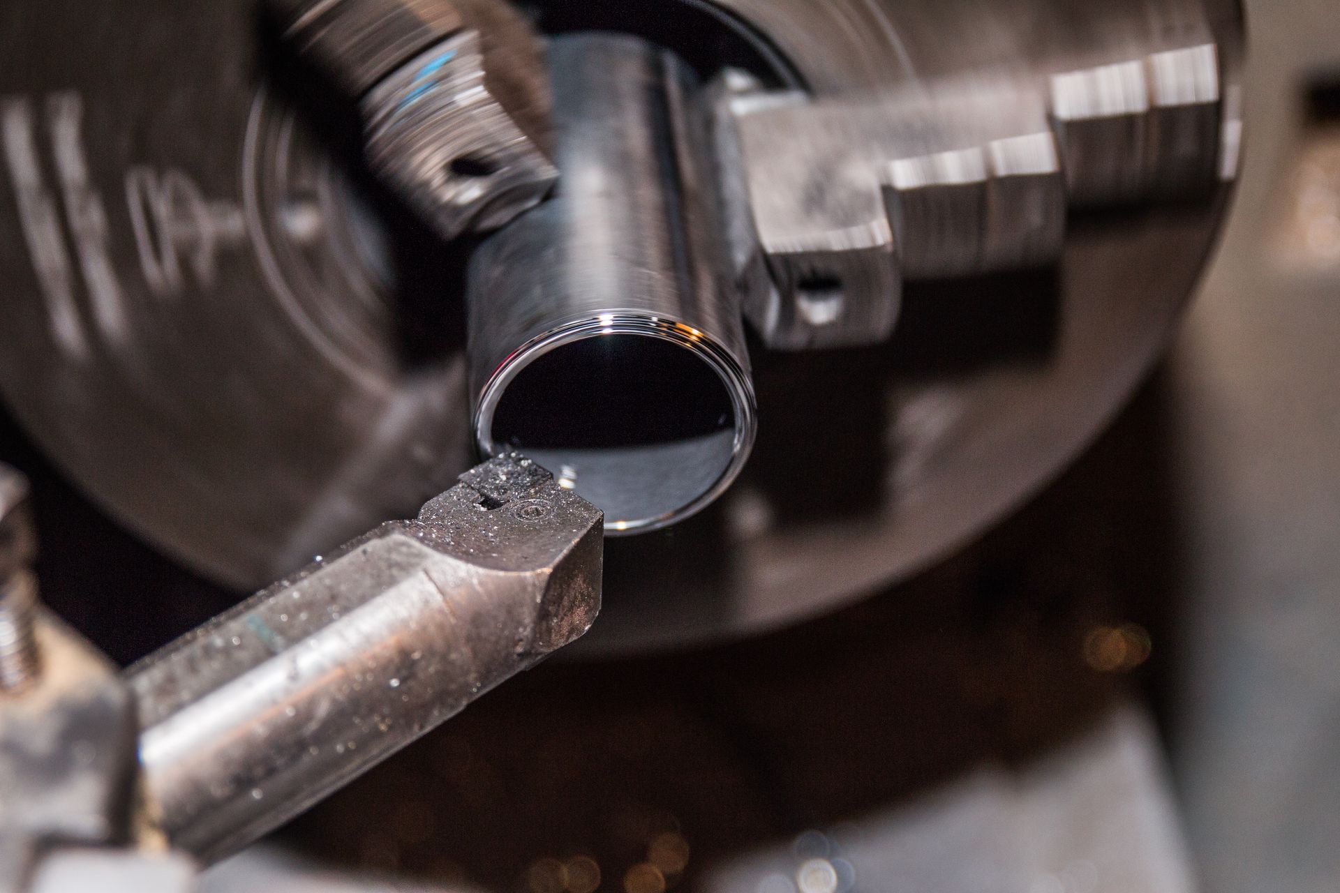 Gros plan sur un tour à métaux usinant un tuyau cylindrique avec un outil de coupe.
