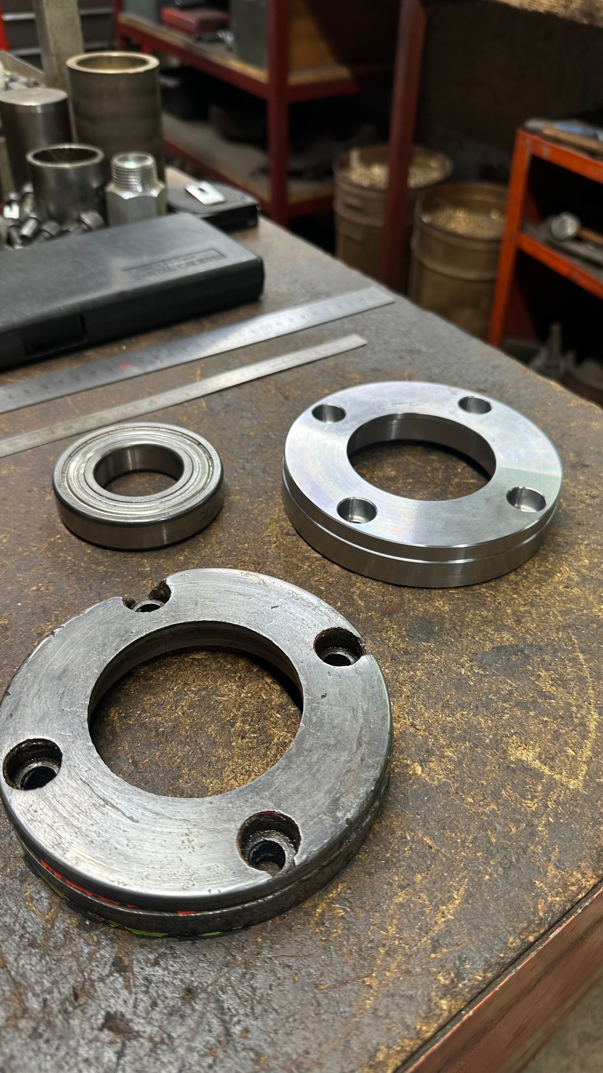 Trois anneaux métalliques usinés posés sur un établi dans un atelier