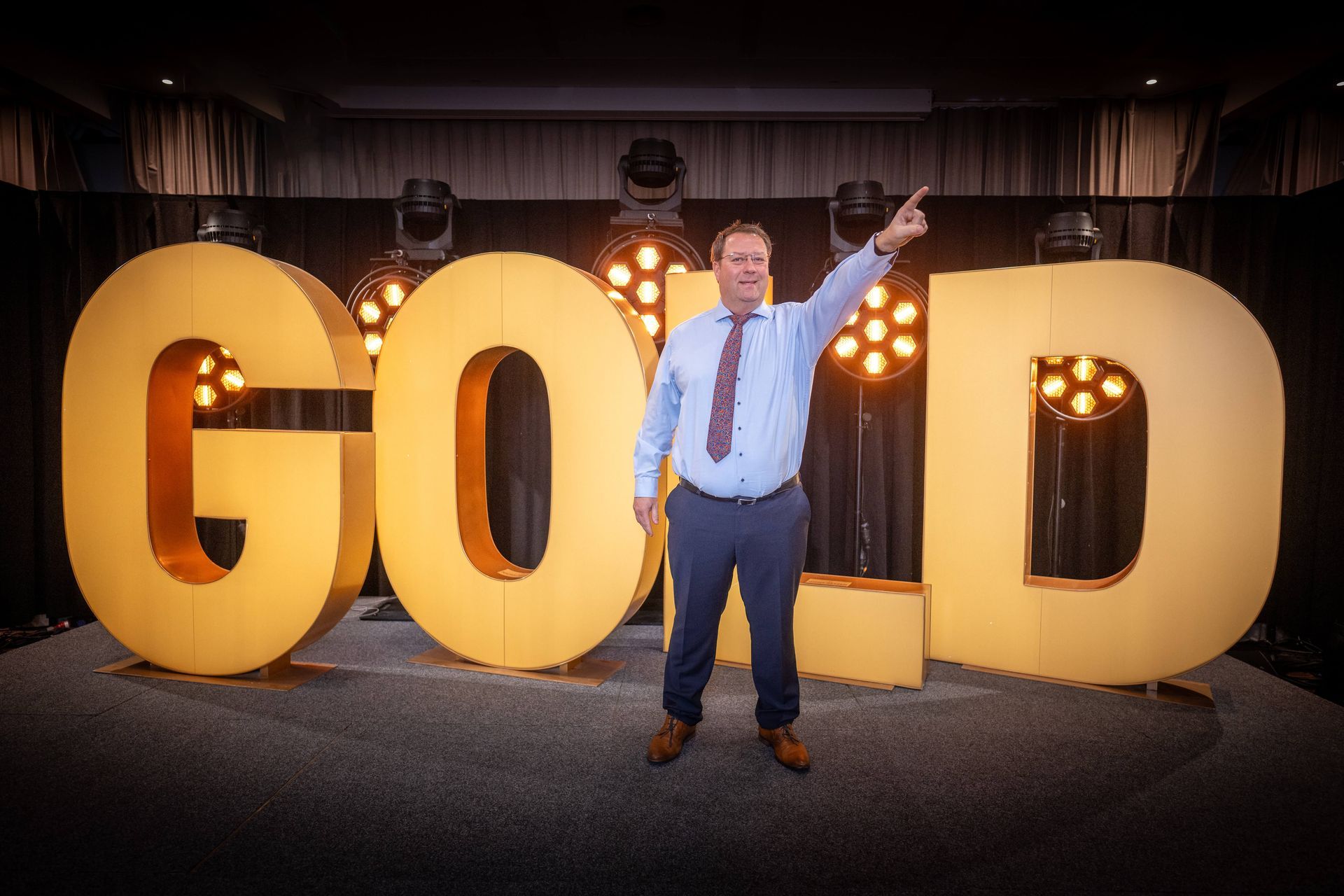 Ein Mann steht vor einem großen goldenen Schild