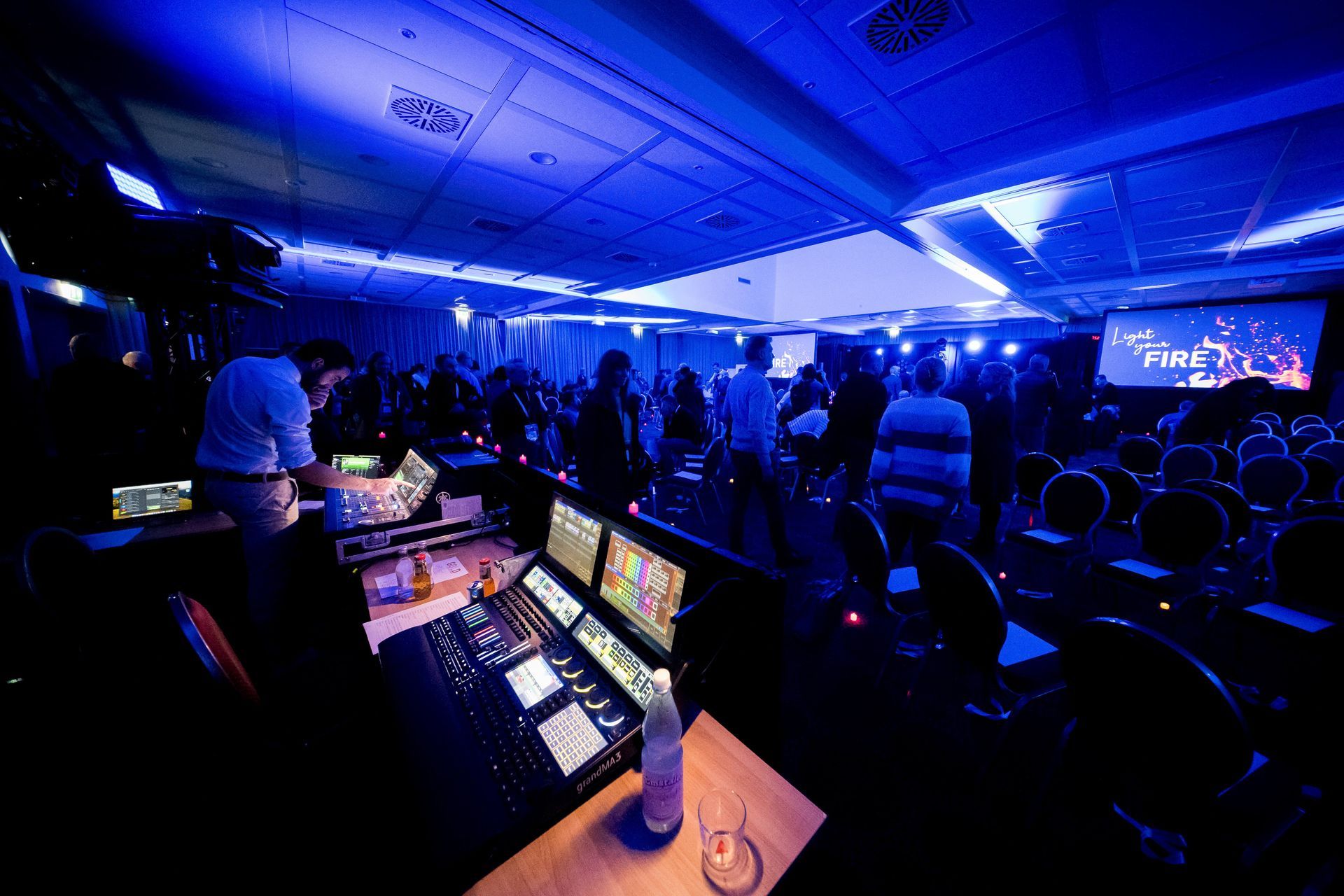 Eine Gruppe von Menschen hat sich in einem großen, blau beleuchteten Raum versammelt.