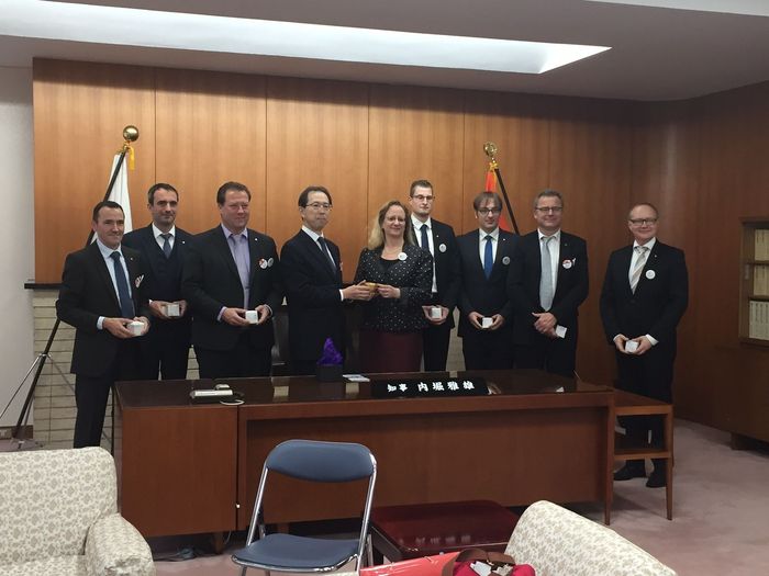 Eine Gruppe von Menschen in Anzug und Krawatte posiert in einem Raum für ein Foto.