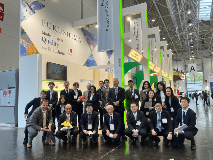 Eine Gruppe von Menschen posiert für ein Foto vor einem Schild mit der Aufschrift „Fukushima“