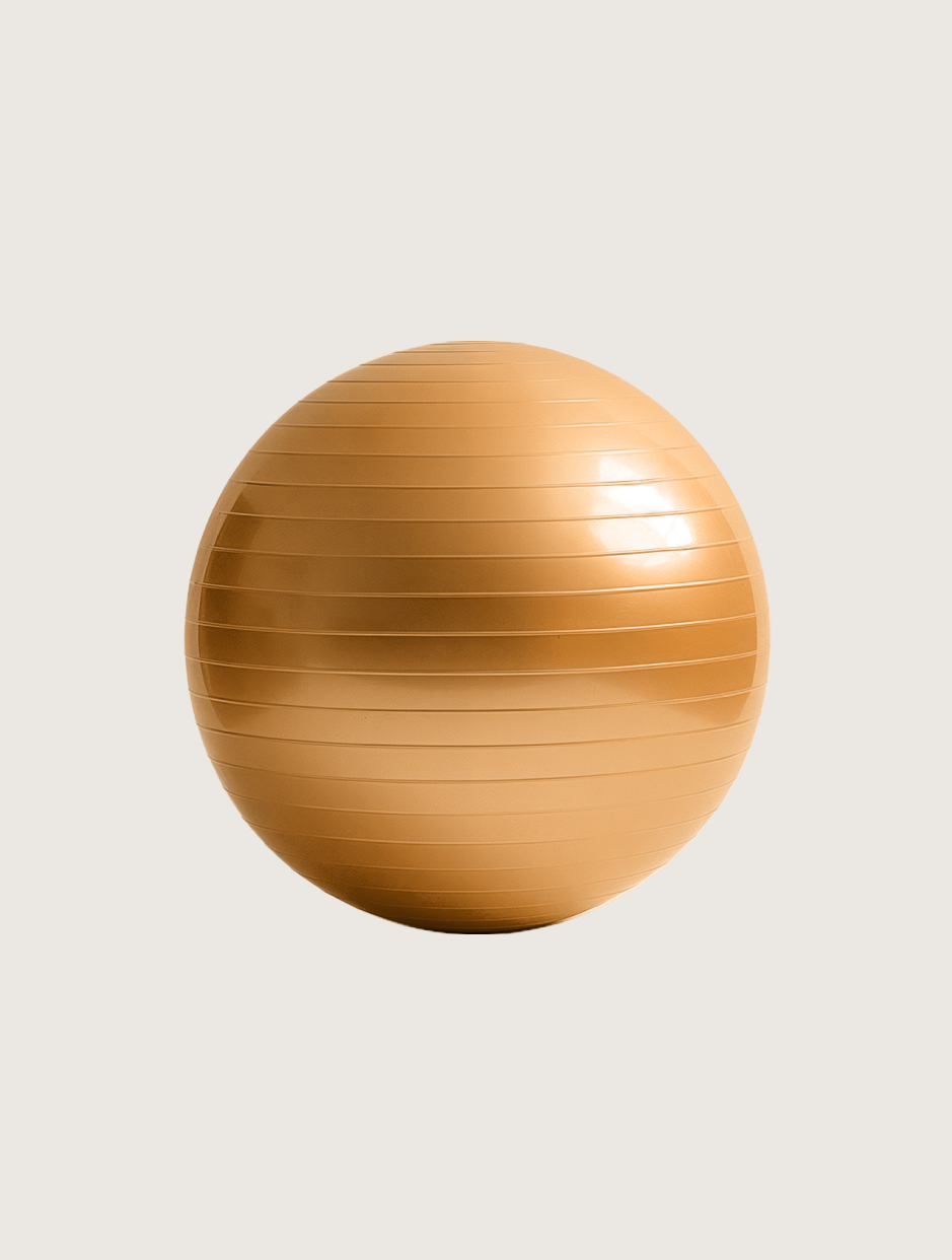 Ein goldener Gymnastikball liegt auf einer weißen Oberfläche.
