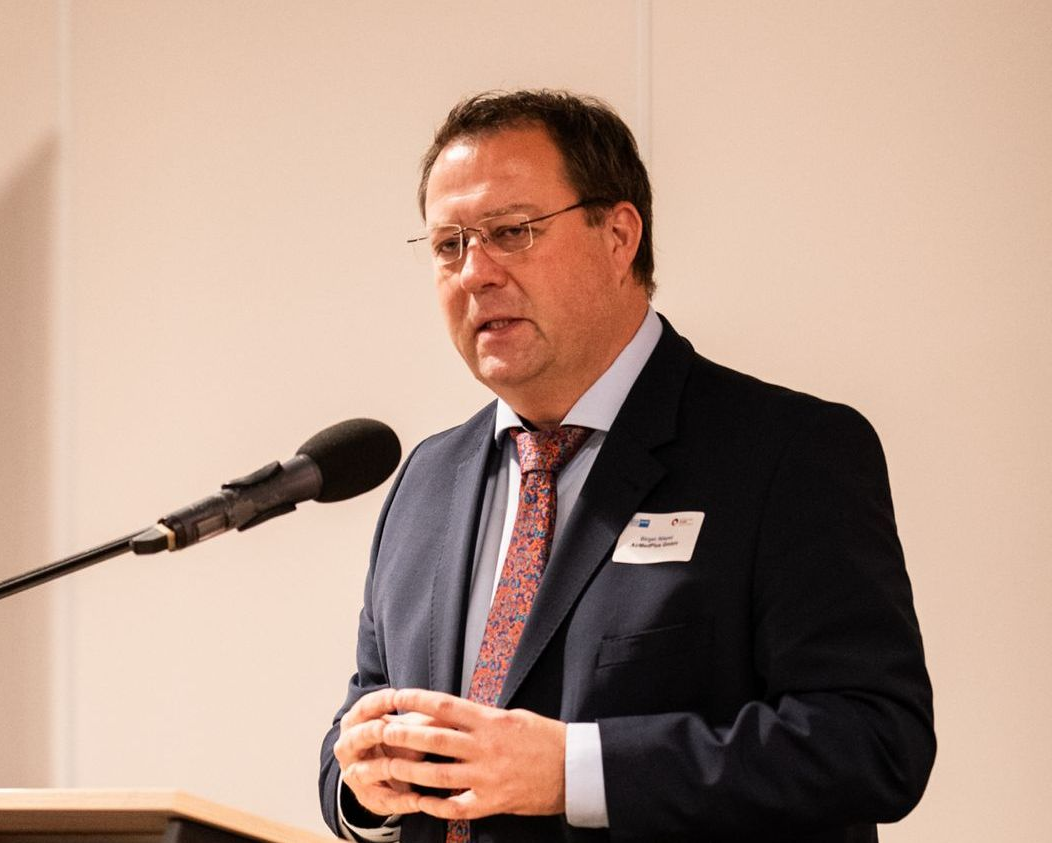 Ein Mann im Anzug spricht auf einem Podium vor einem Publikum.