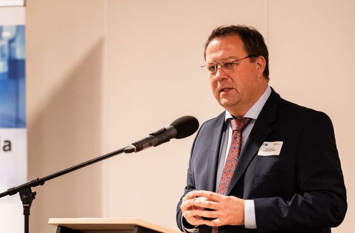 Ein Mann in Anzug und Krawatte spricht in ein Mikrofon.