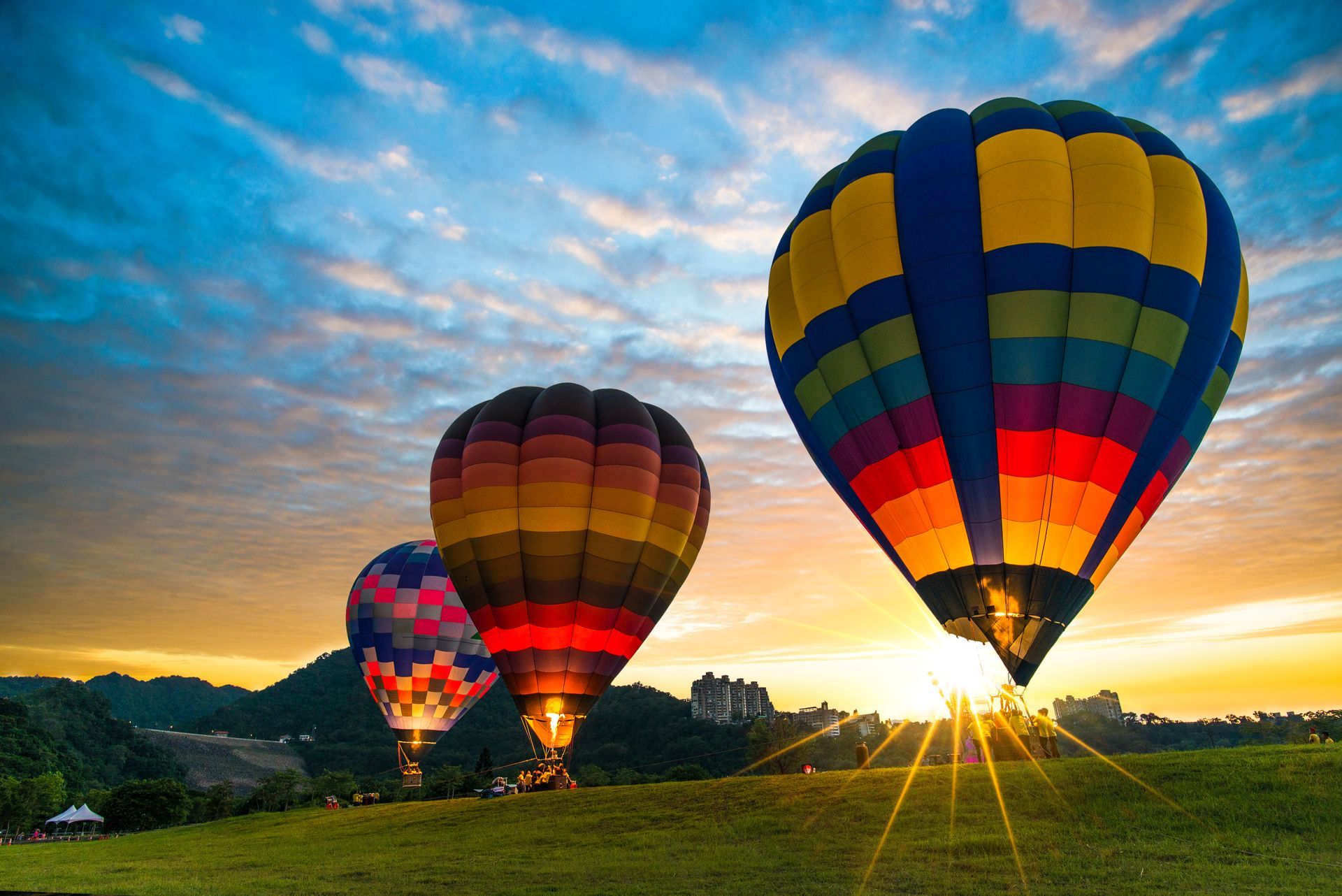 Décollage de trois montgolfières colorées.