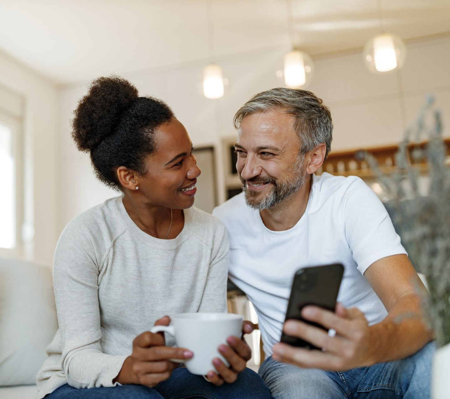 Couple souriant devant un téléphone.