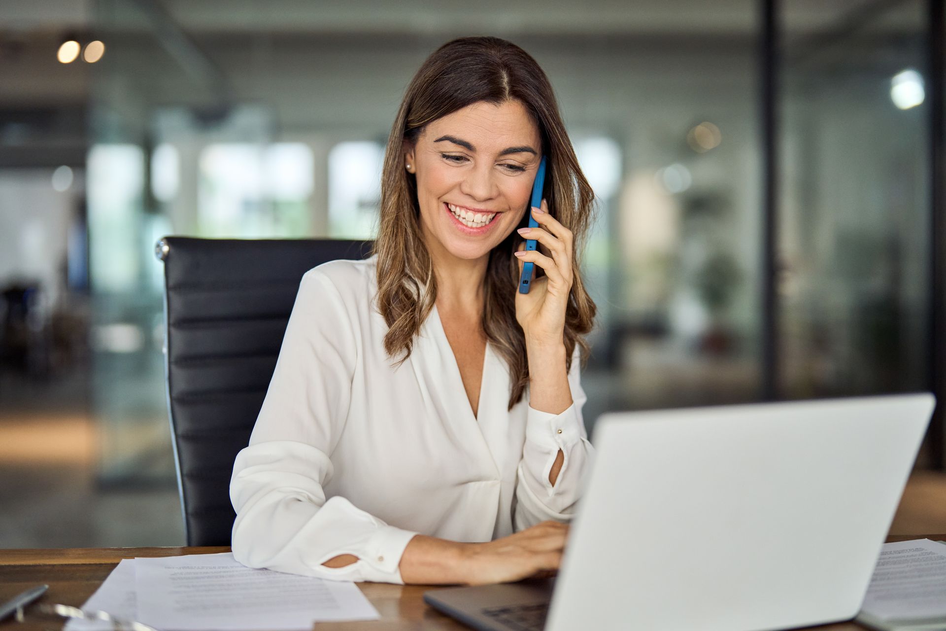 Personne répondant au téléphone derrière son ordinateur portable.