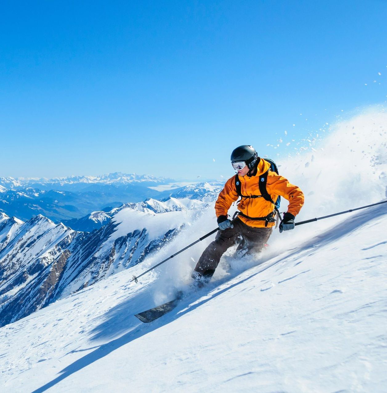 Pratique du ski par un jeune homme en tenue orange.