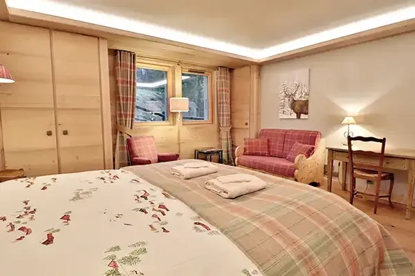 Chambre avec grand lit et canapé du chalet Le Bois du Bouchet à Combloux.